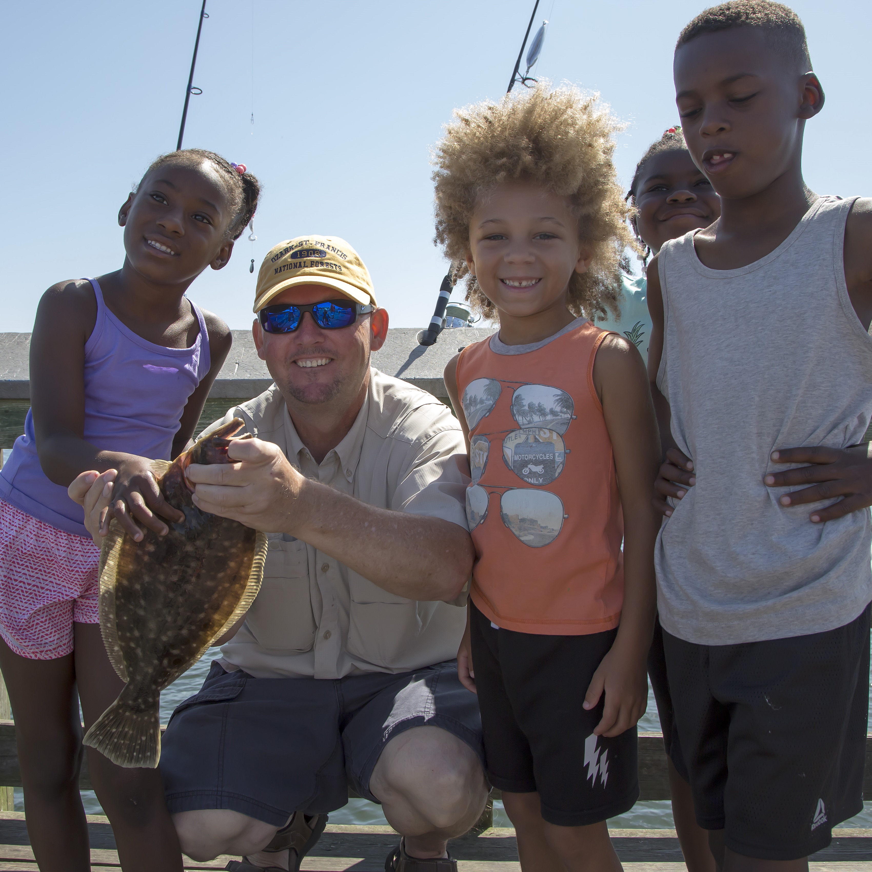New anglers catching a fluke with a certified CARE fishing instructor.