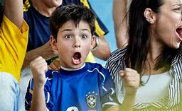 Picture of young boy in a blue sports jersey intensely cheering in a crowd.
