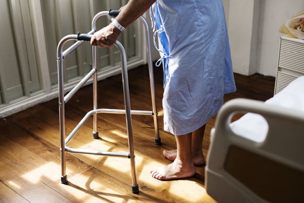 A person in a hospital gown using a walker