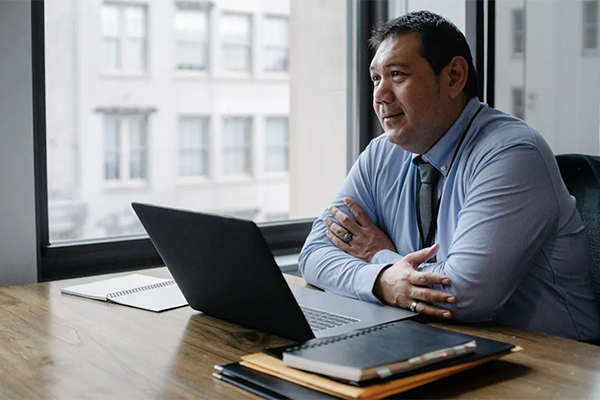 Man sitting at his office desk with an open laptop.