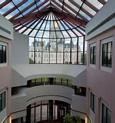 View from a balcony of the inside of a large white building with huge windows spanning the wall and ceiling 