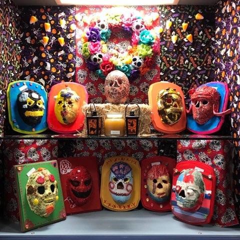 Art displayed at Solnit North in a case, including small, colorful, decorative masks