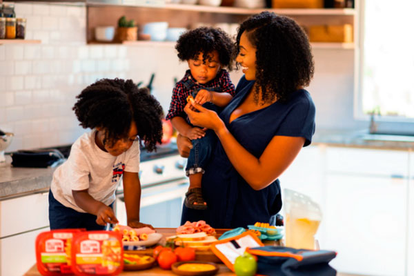A smiling mother and her two kids preparing food in the kitchen